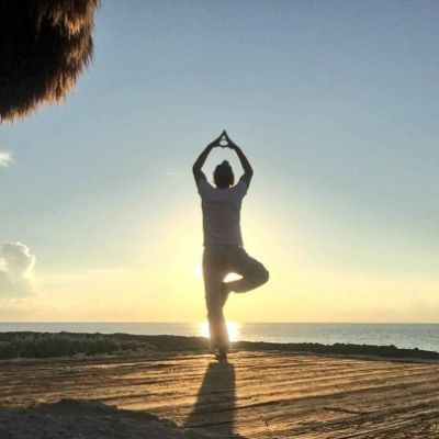 Valentino Lanus doing a tree pose in front of the rising sun.